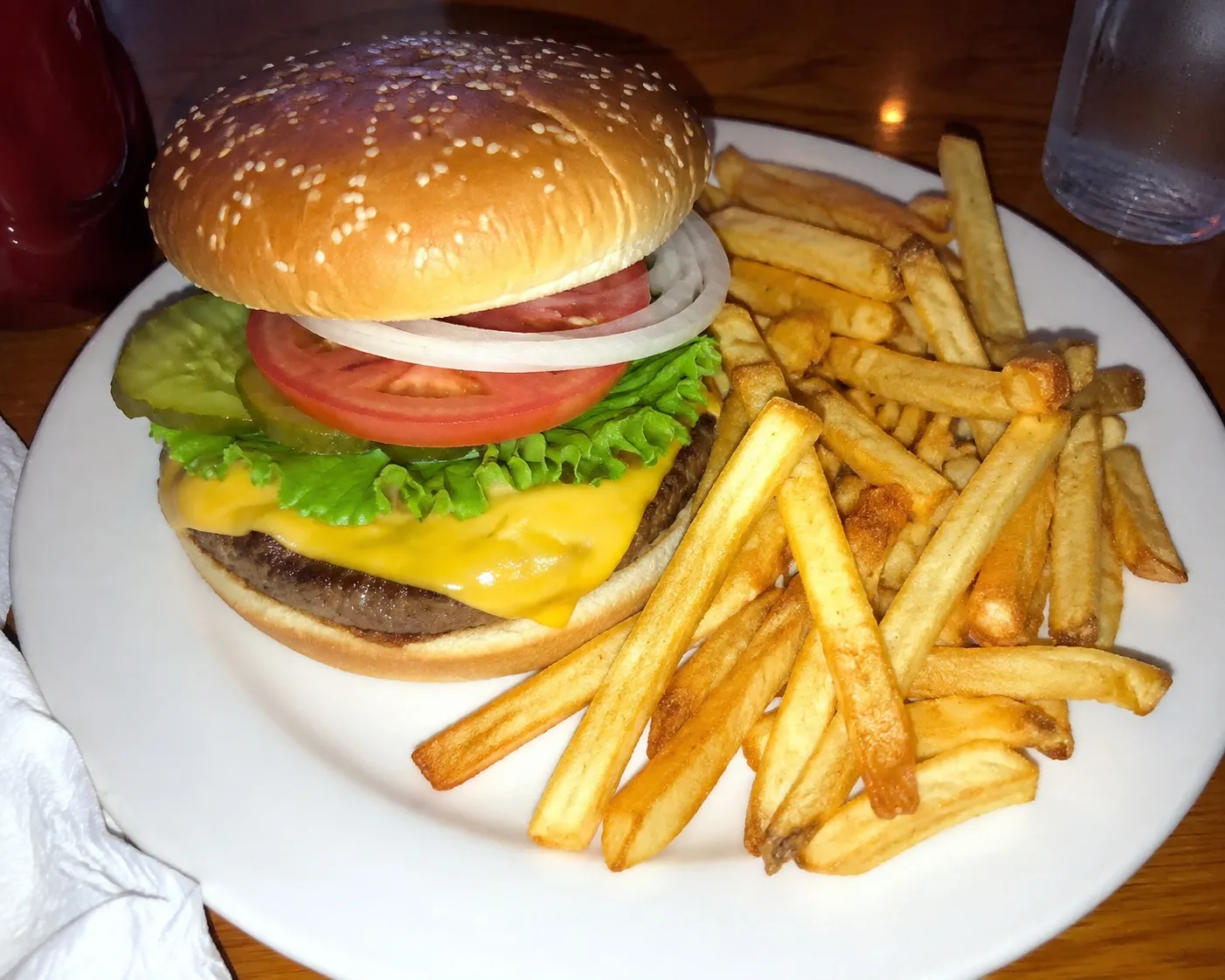 A cheeseburger and fries photographed at the table under restaurant light