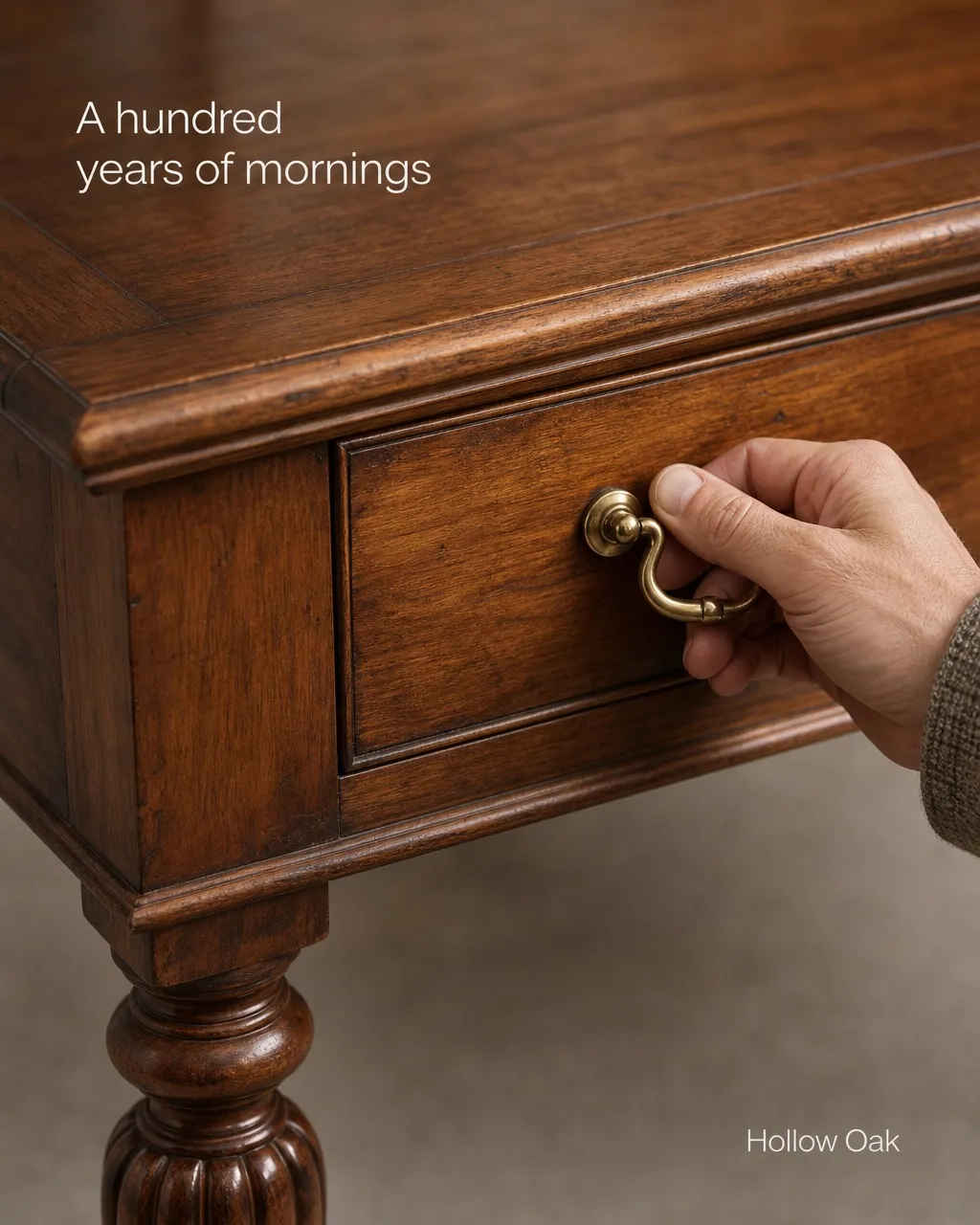 An ad for an antique writing table: a hand on one brass drawer pull, the headline set into the top of the photograph