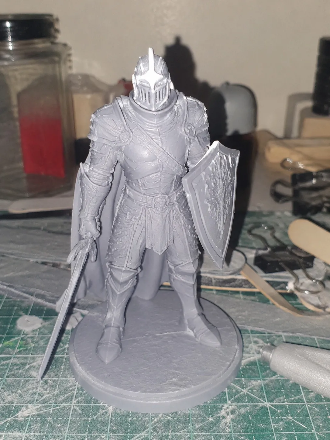 An unpainted resin knight miniature photographed on a hobby desk