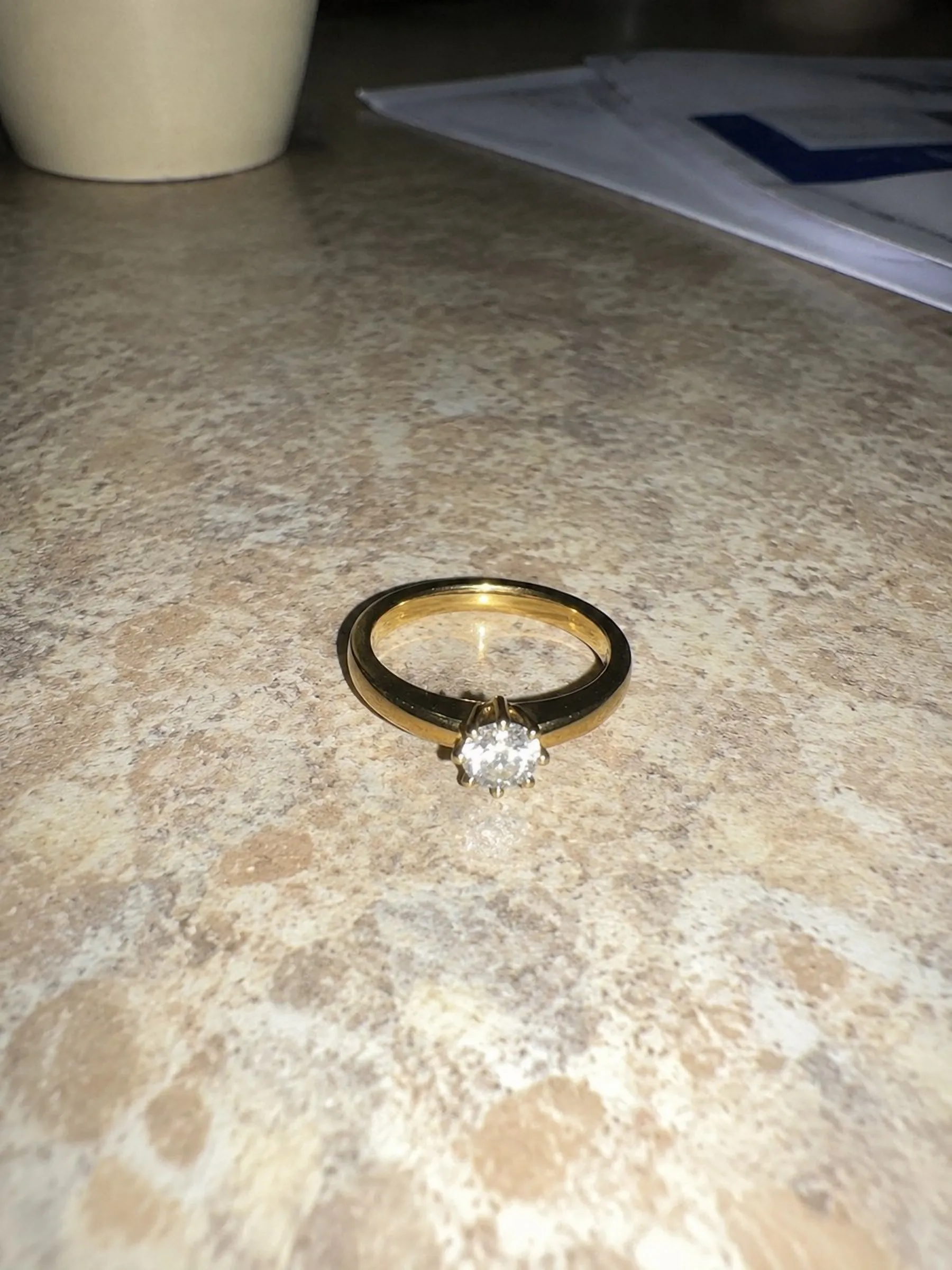 a diamond solitaire ring, photographed on a phone