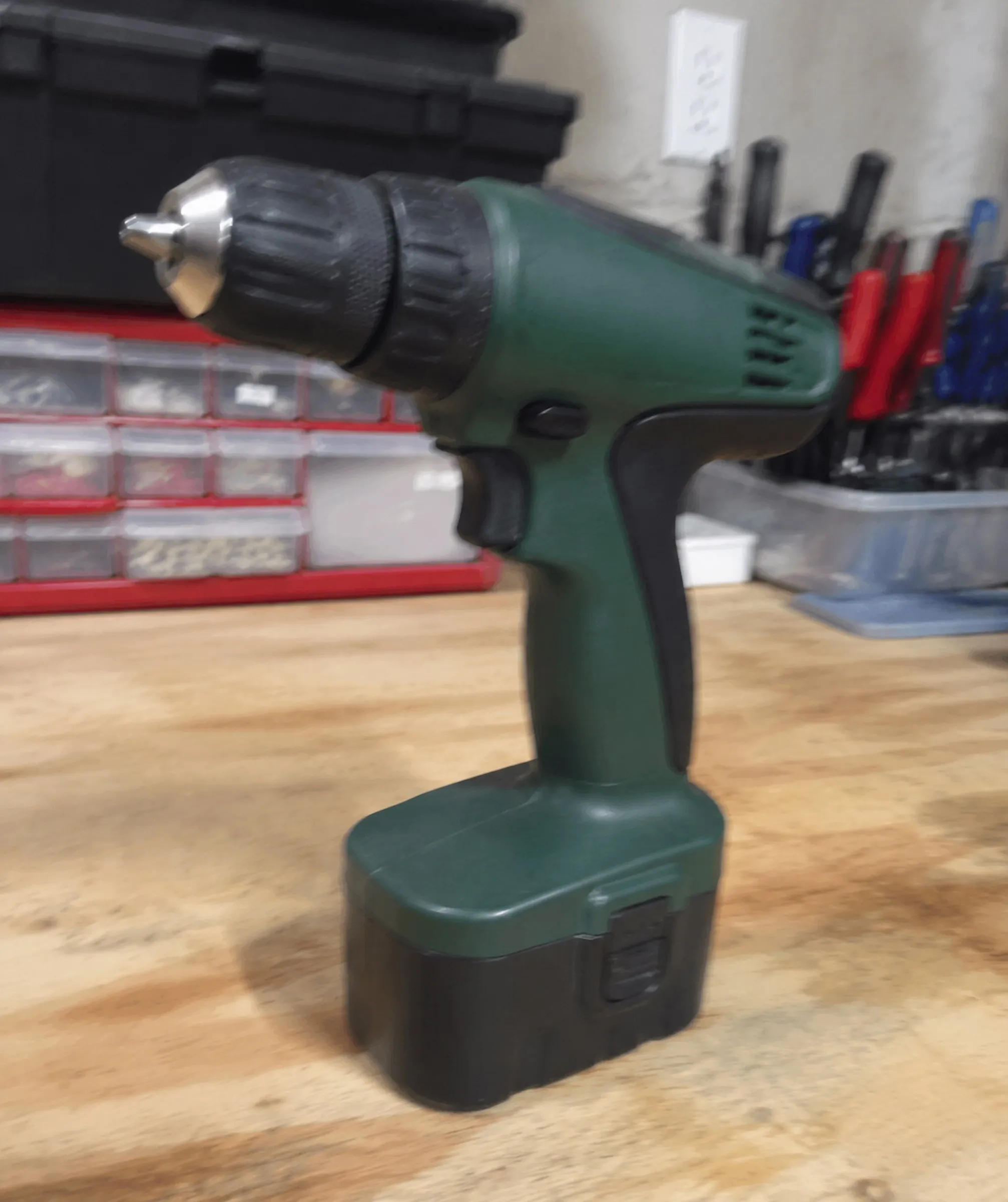 A green cordless drill photographed on a workbench